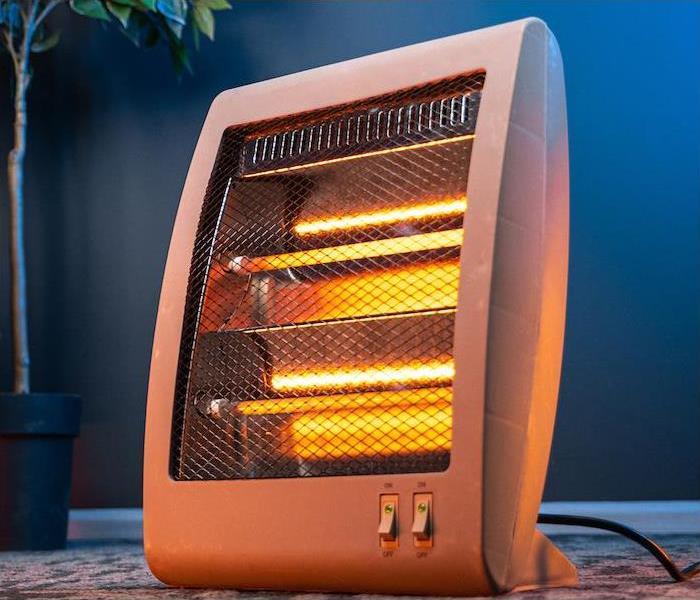 ”heater” alt = "a small electric heater in a living room” 